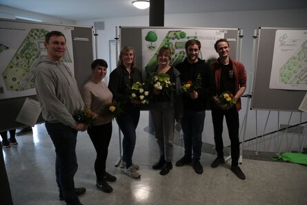 Menschen mit Blumensträußen vor aufgehängten Entwürfen