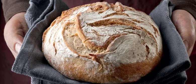 Zwei Hände halten einen Laib Brot.