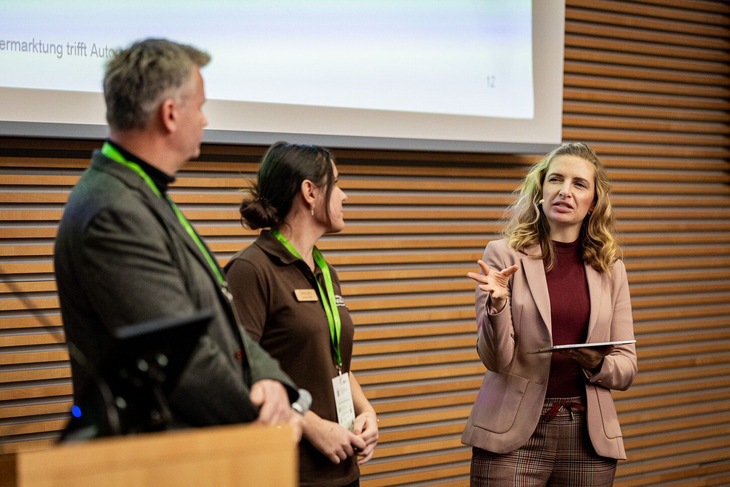 Das Bild zeigt die Referenten Frau Sigl und Herrn Börner zusammen mit der Moderatorin Frau Mehner auf der Bühne des Forum Regionalvermarktung 2024